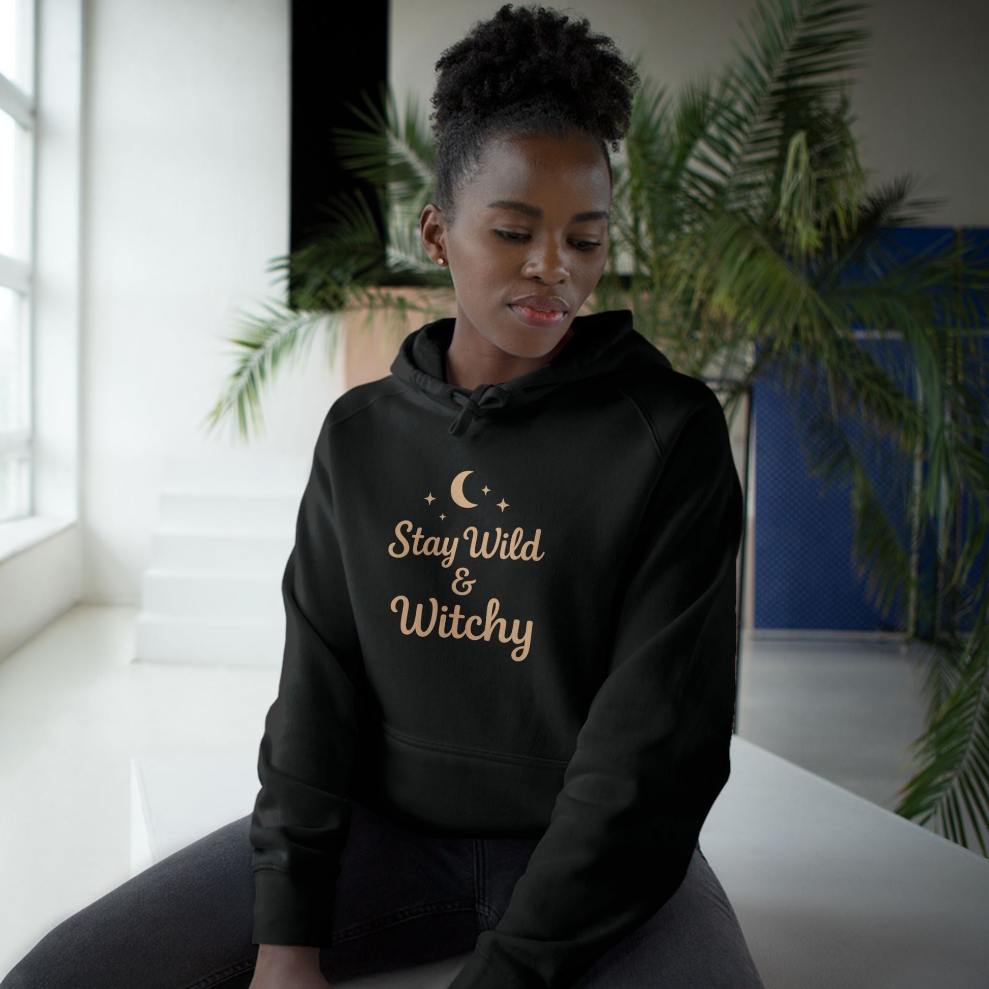 Woman in black Witchy Supply Hoodie featuring 'Stay Wild & Witchy' text, ideal for cozy, mystical, and gender-neutral fashion.