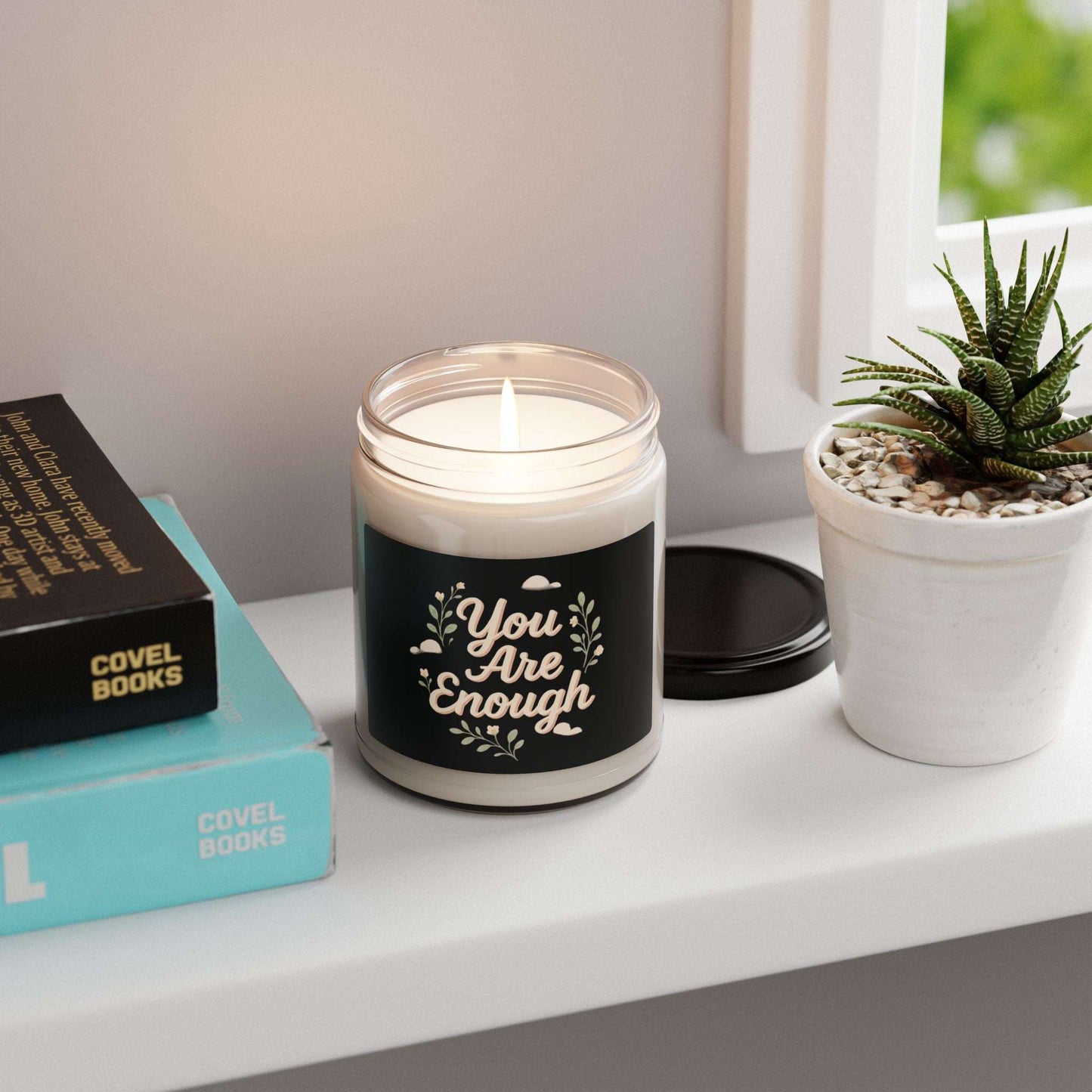 You Are Enough – 9oz soy candle on a windowsill beside books and a succulent, perfect motivational gift and home fragrance accent.
