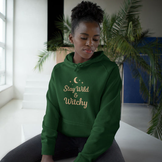 Green hoodie with “Stay Wild & Witchy” printed design, modeled in a cozy indoor setting — Dream Studio Prints.