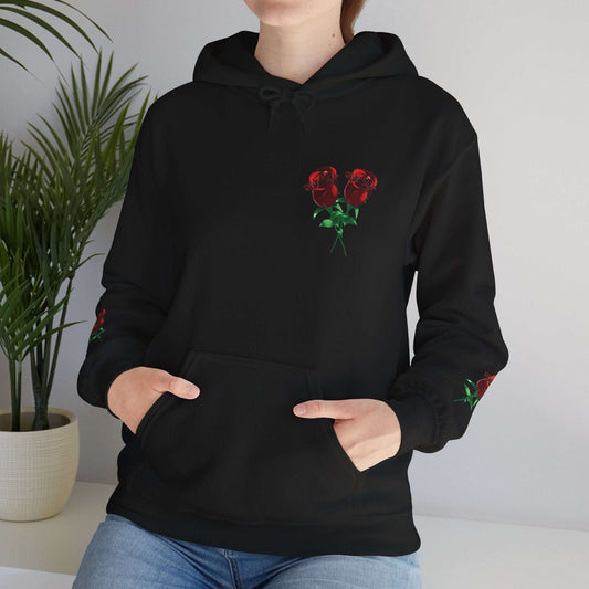 Person wearing a black hoodie with red rose designs on the sleeves and chest, standing indoors.