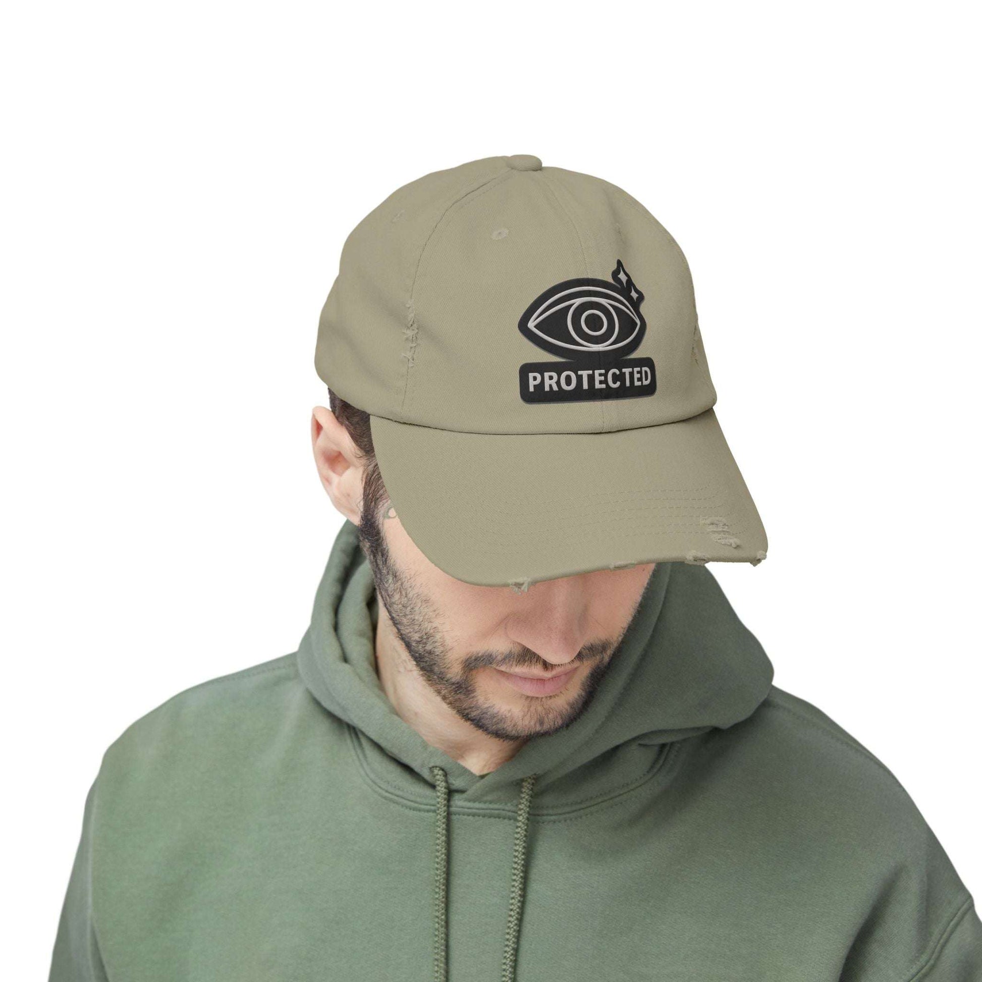 Olive green Protected Eye Distressed Dad Hat worn by man in green hoodie. Embroidered eye design on casual unisex cap.