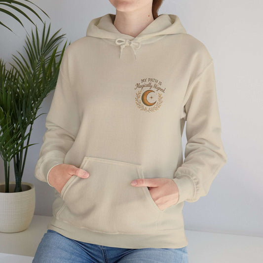 Woman wearing the Aligned Path Moon Hoodie in beige with crescent moon and 'My Path Is Magically Aligned' text, ideal for spiritual self-care.