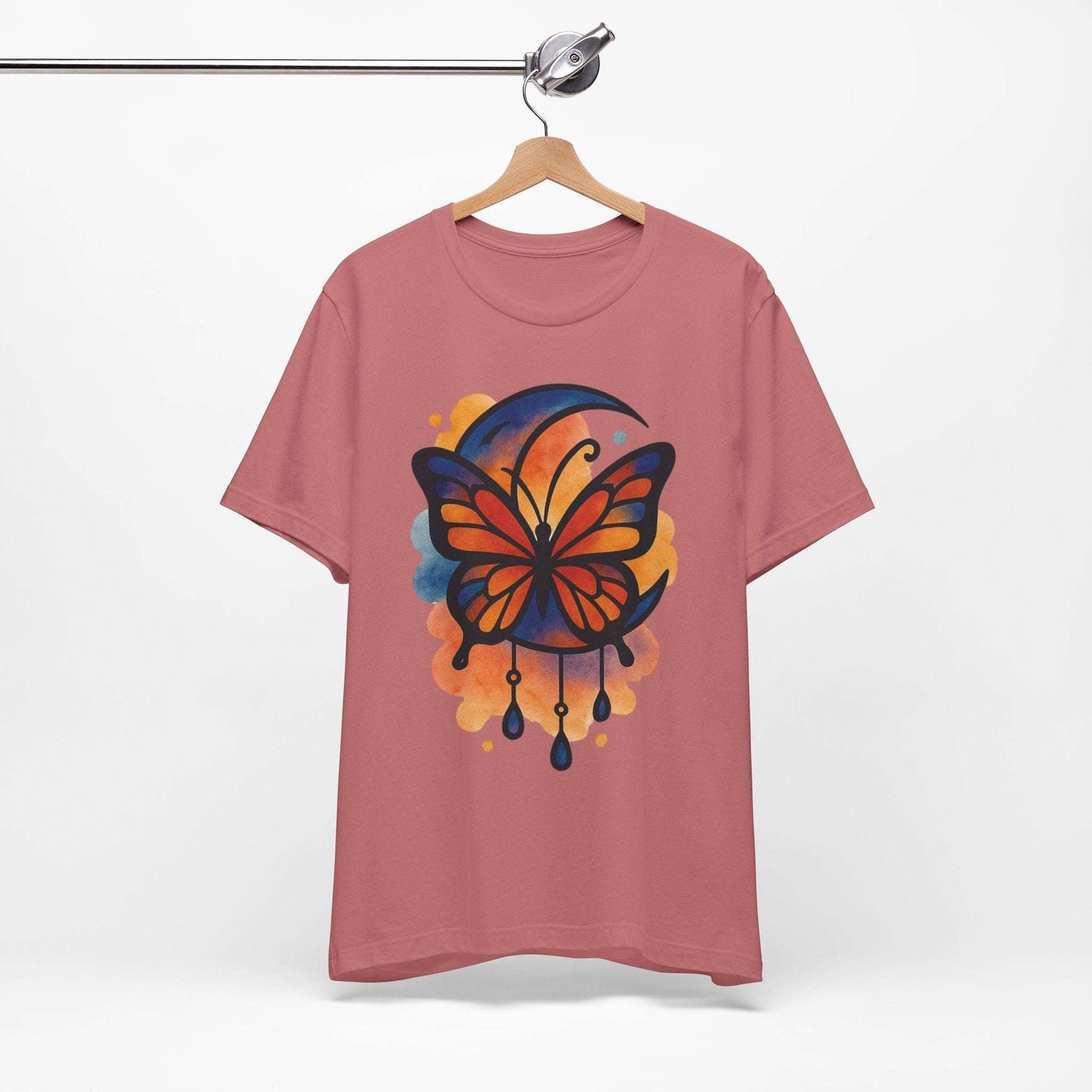 Pink t-shirt with a colorful butterfly design on a hanger against a white background