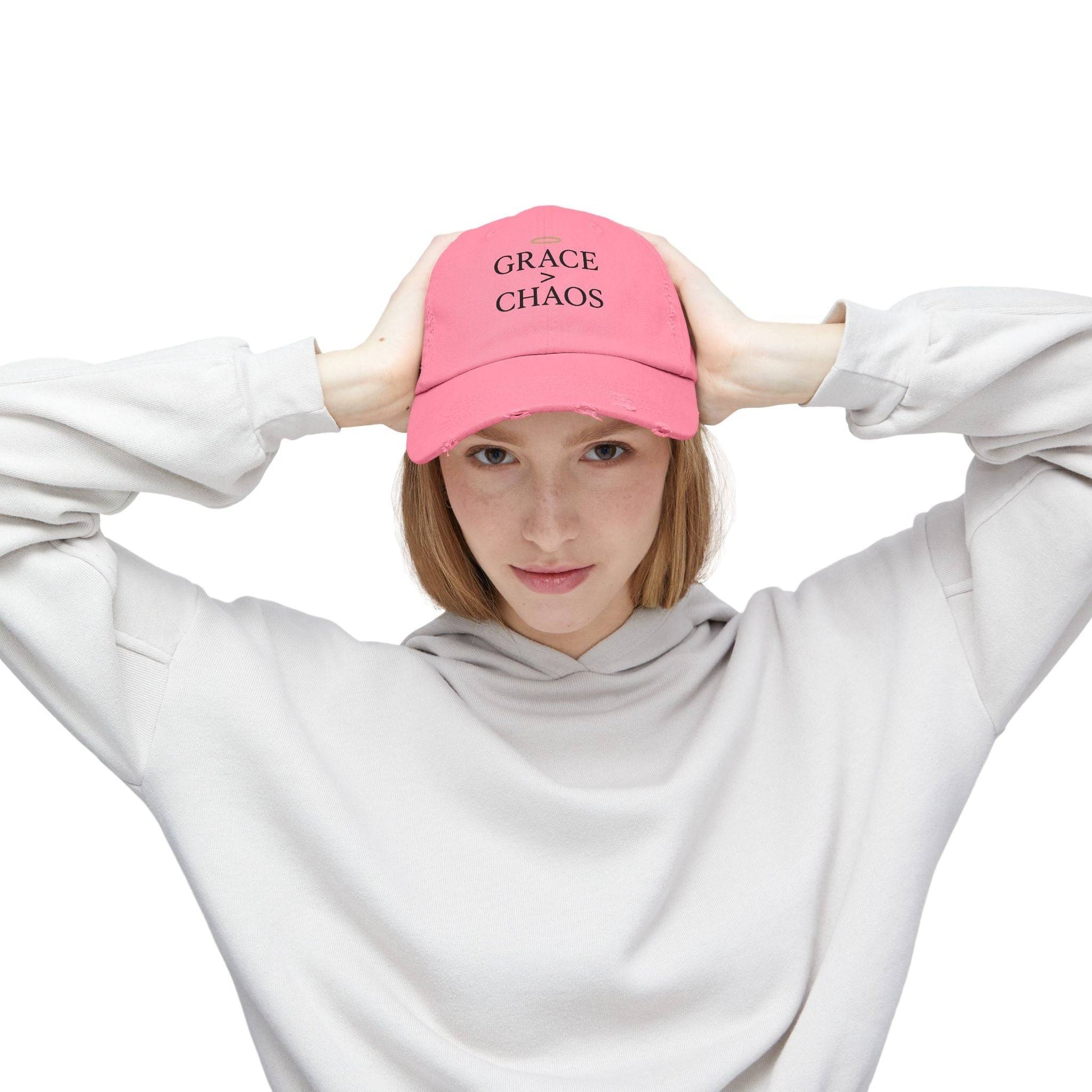 Woman wearing pink Grace > Chaos Embroidered Distressed Cap, a motivational baseball hat for gifting or casual outdoor style.