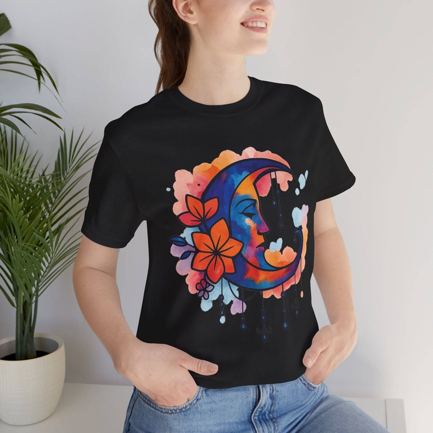 Black Floral Moonface Goddess Tee with vivid crescent moon and hanging charms, a bold boho graphic tee for moon lovers and festival goers.