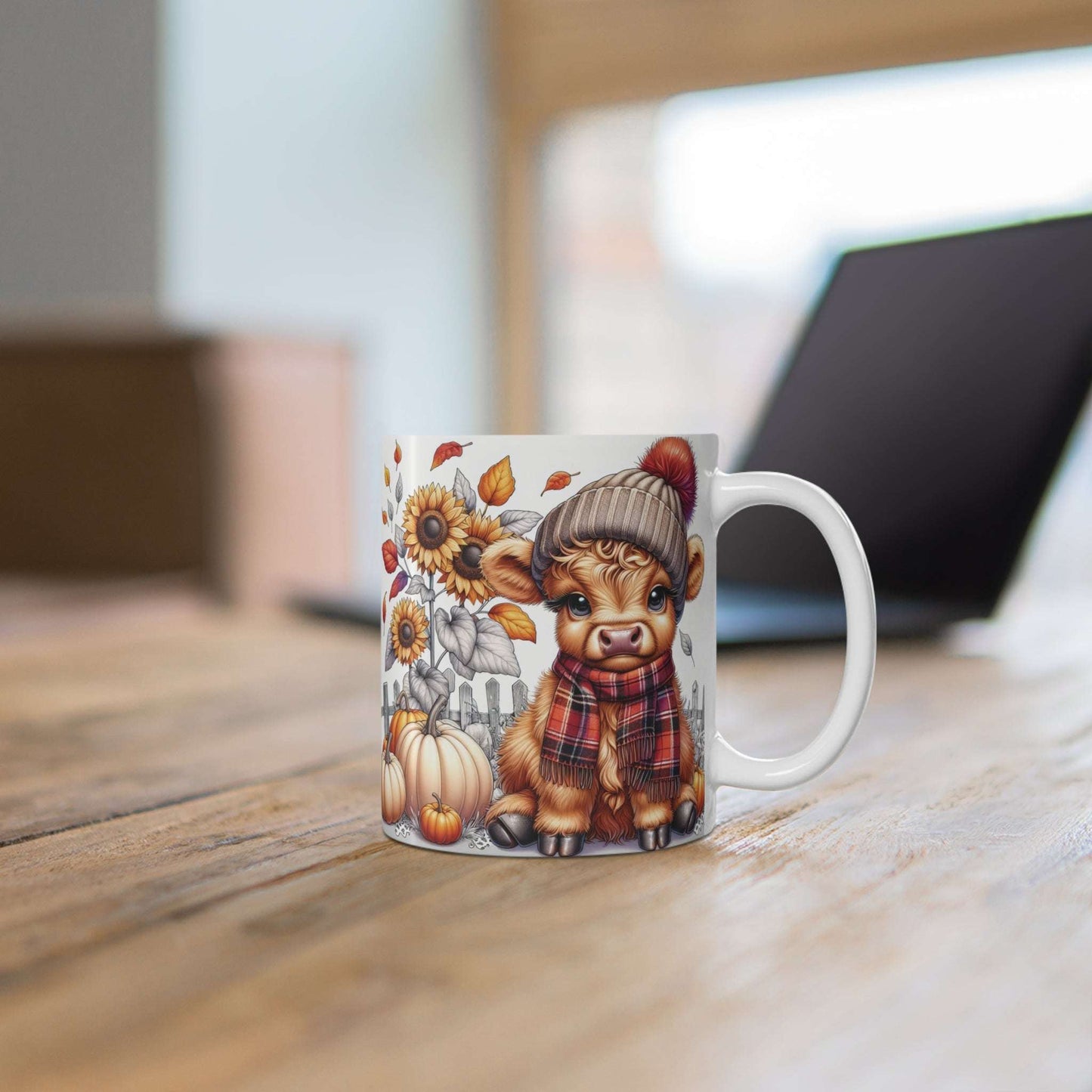 Mug with a cow wearing a hat and scarf design on a wooden surface.