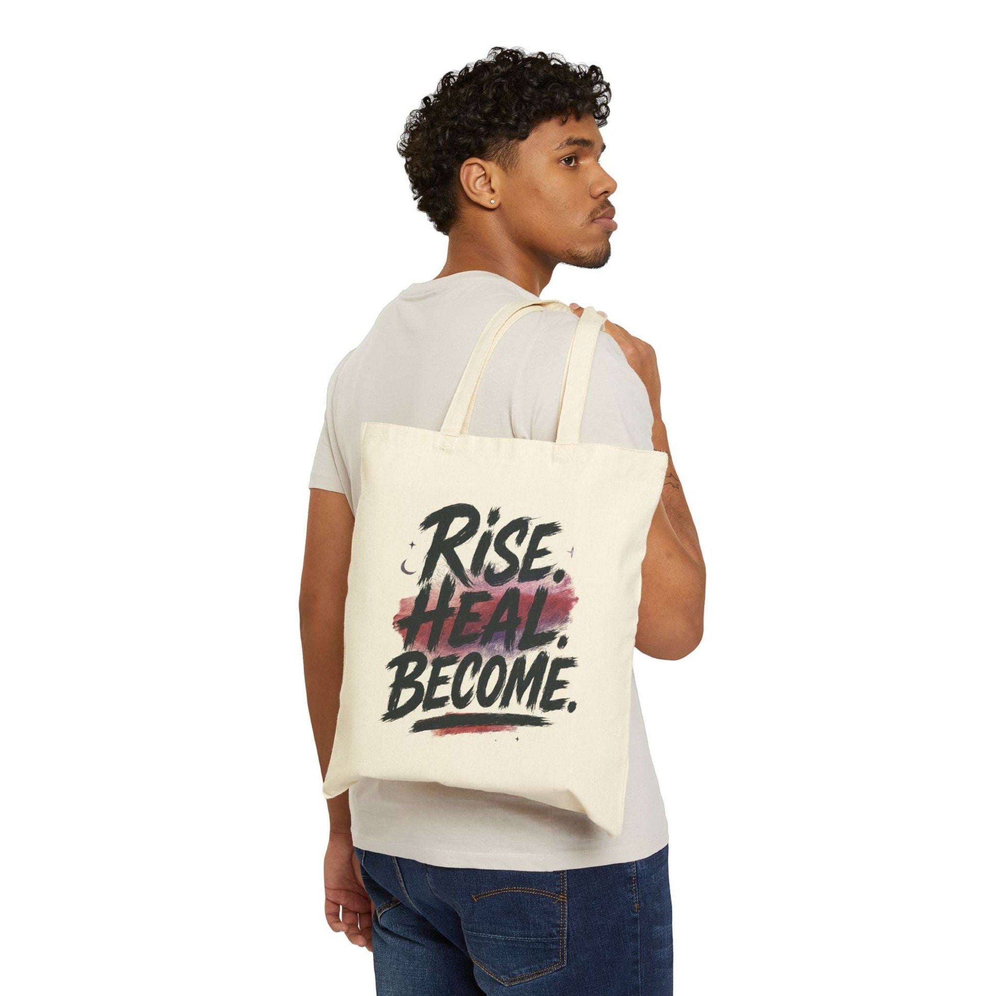 Man carrying the Rise Heal Become Tote Bag – Inspirational Canvas Shopper with motivational quote, showcasing its size and casual everyday style.