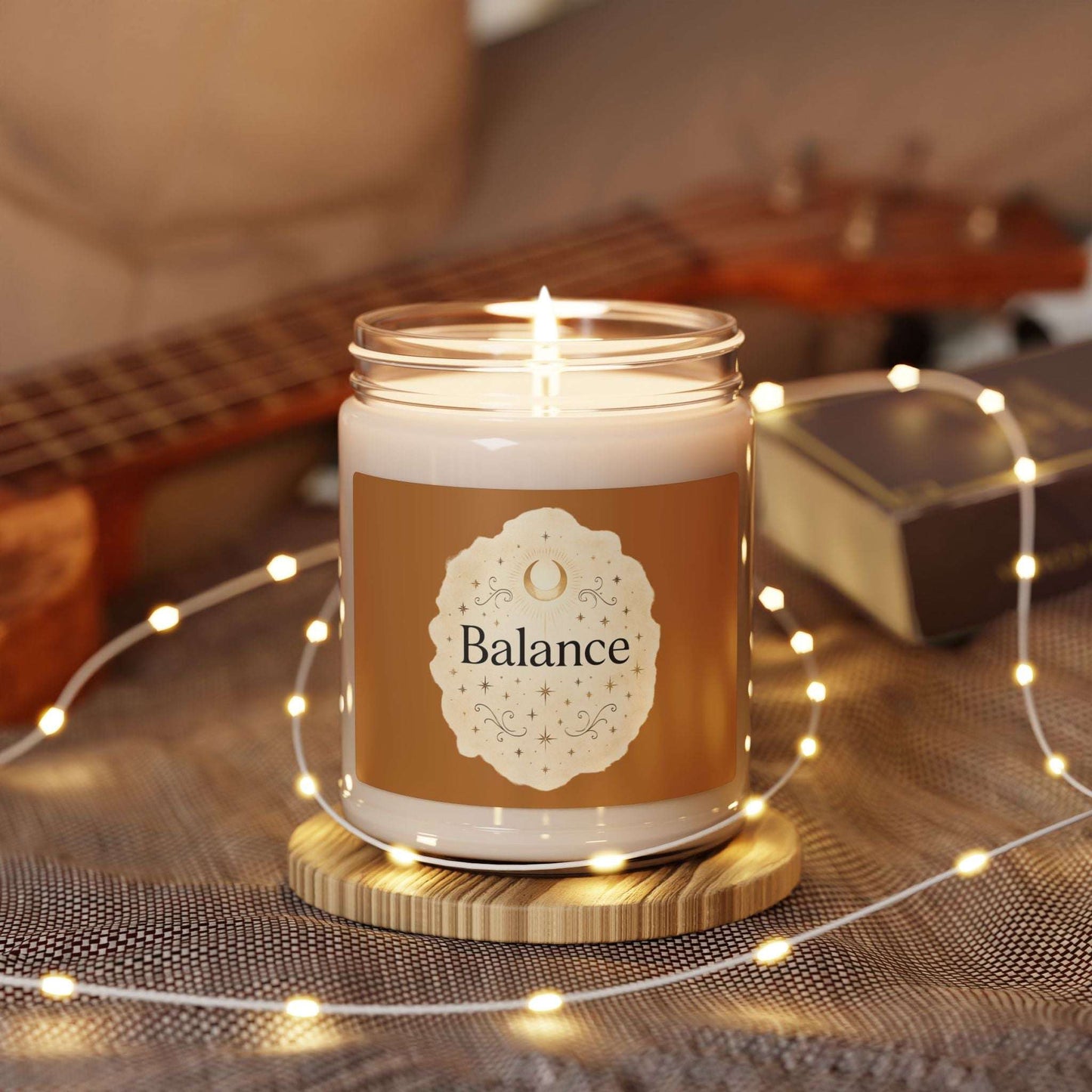 Candle in a jar labeled 'Balance' with a guitar and string lights in the background