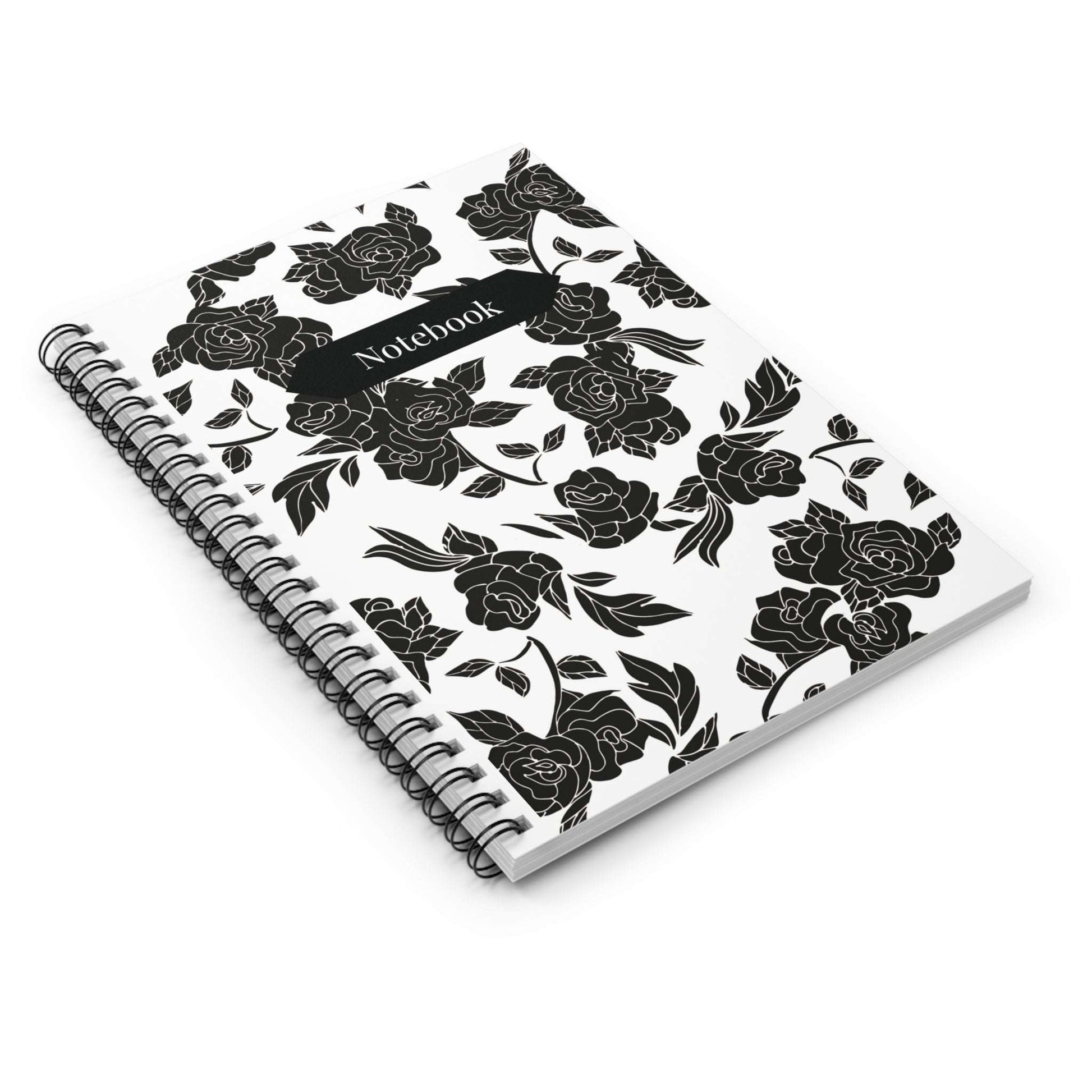 Notebook lies flat with a black floral design on a white surface