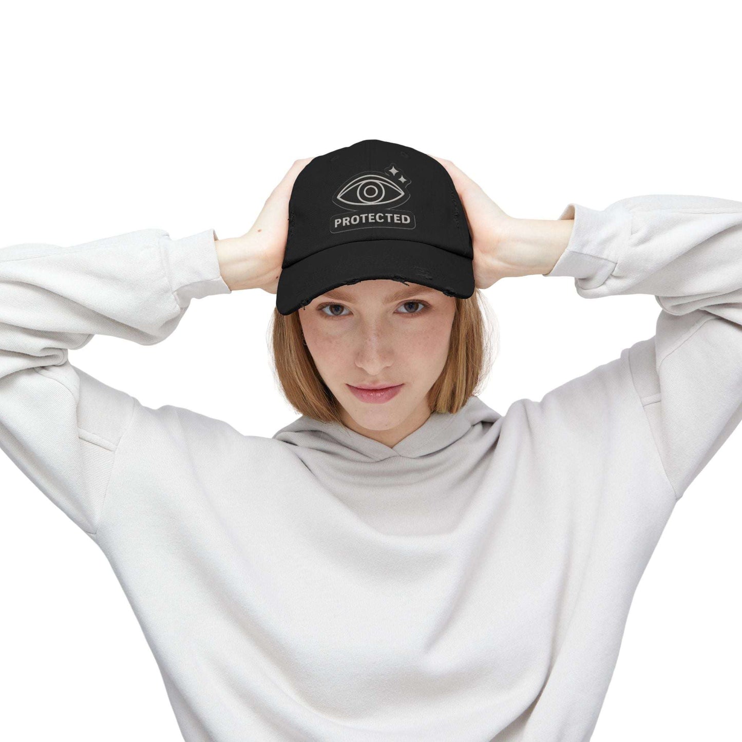 Black Protected Eye Distressed Dad Hat worn by woman in white hoodie. Embroidered eye design on vintage-style unisex cap.