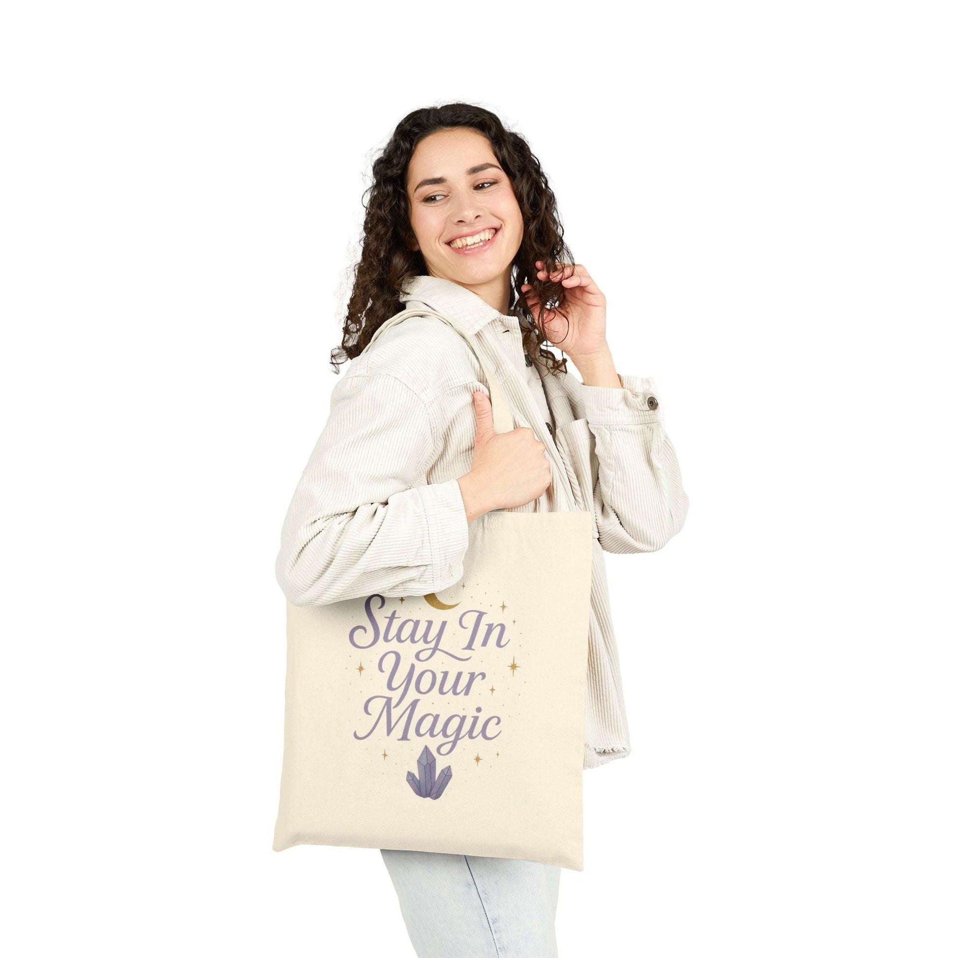 Woman holding canvas tote bag with inspirational quote 'Stay In Your Magic', casual everyday outfit, lifestyle photography.