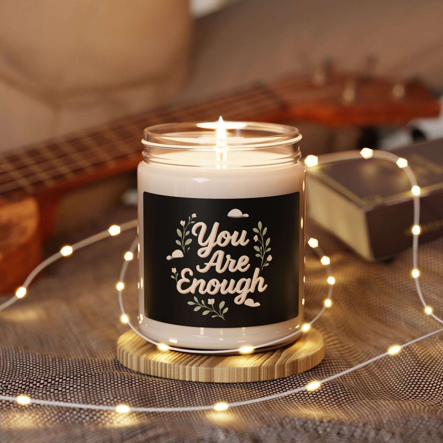 You Are Enough – 9oz inspirational scented soy candle lit on a wooden coaster with fairy lights, ideal for self-care and relaxation decor.