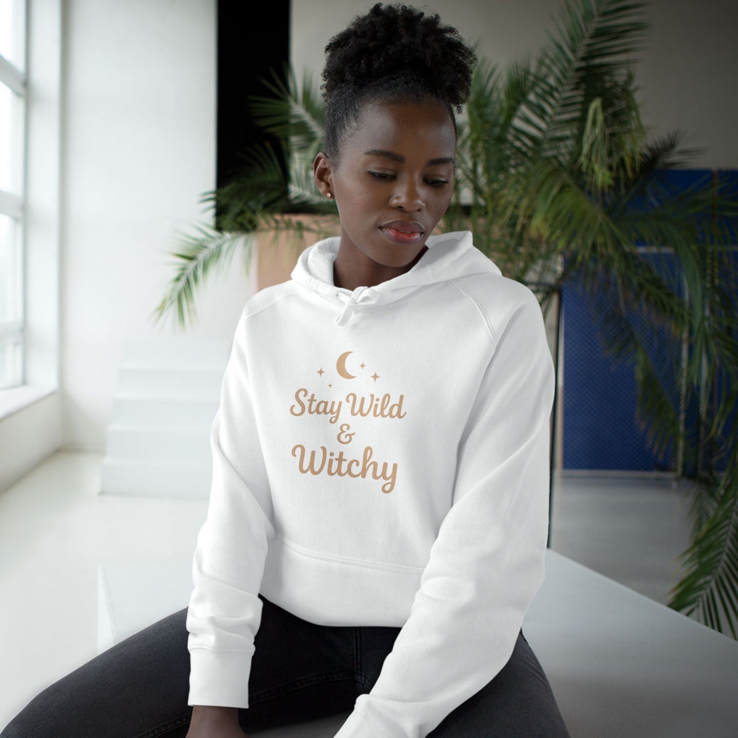 Woman modeling white Witchy Supply Hoodie with celestial 'Stay Wild & Witchy' print, perfect for cozy Wiccan-inspired style.