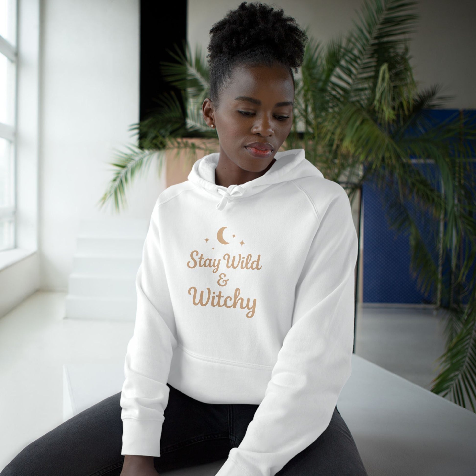 Woman modeling white Witchy Supply Hoodie with celestial 'Stay Wild & Witchy' print, perfect for cozy Wiccan-inspired style.