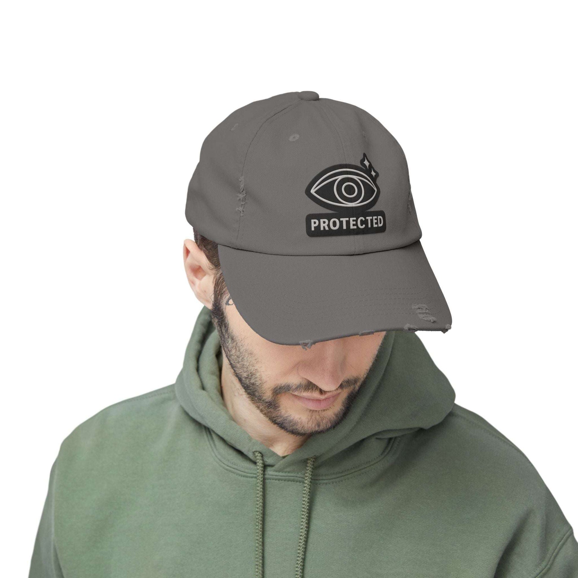 Charcoal gray Protected Eye Distressed Dad Hat worn by man in green hoodie. Urban unisex cap with embroidered eye design.