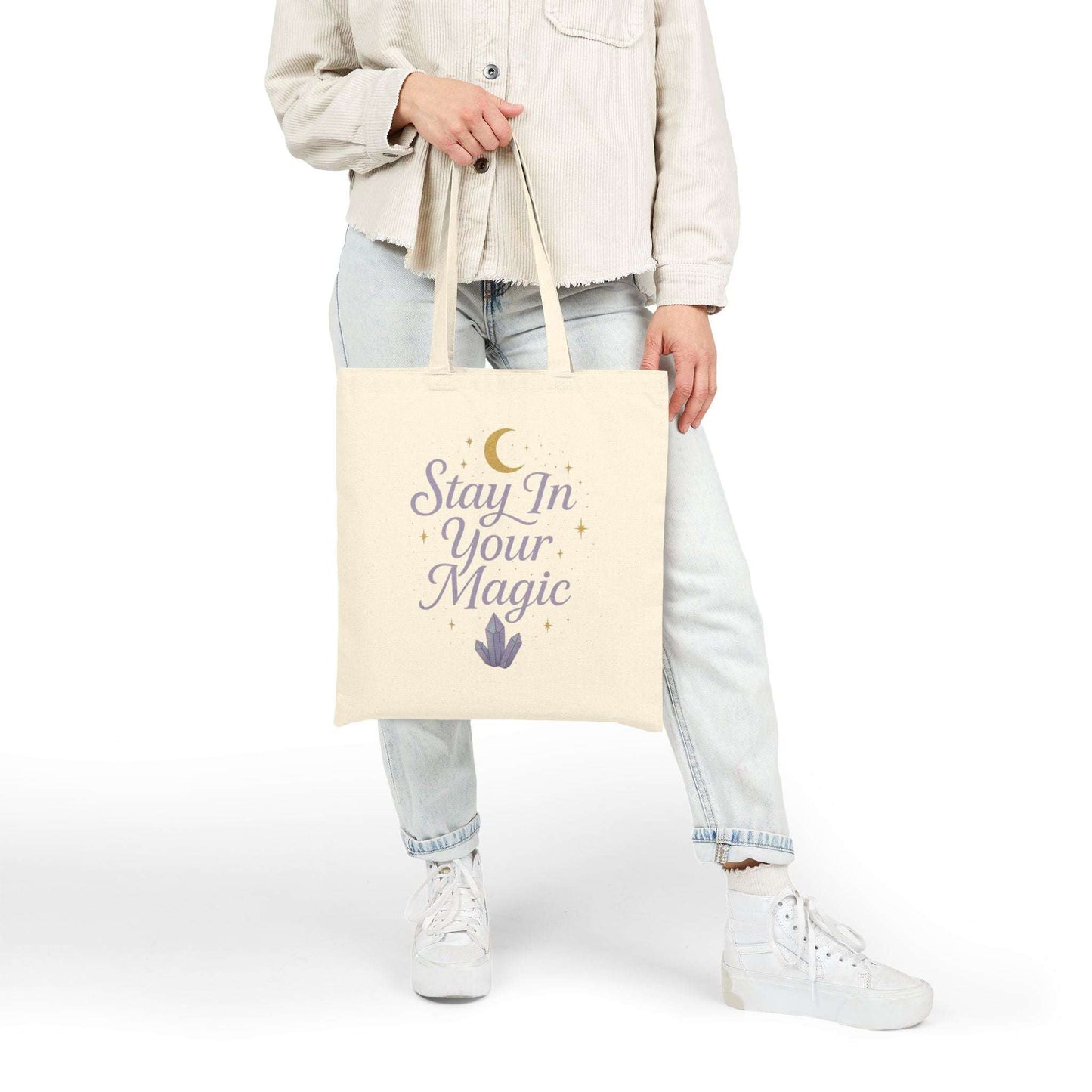 Close-up side view of canvas tote bag with printed quote 'Stay In Your Magic' being carried by a woman, minimalist lifestyle look