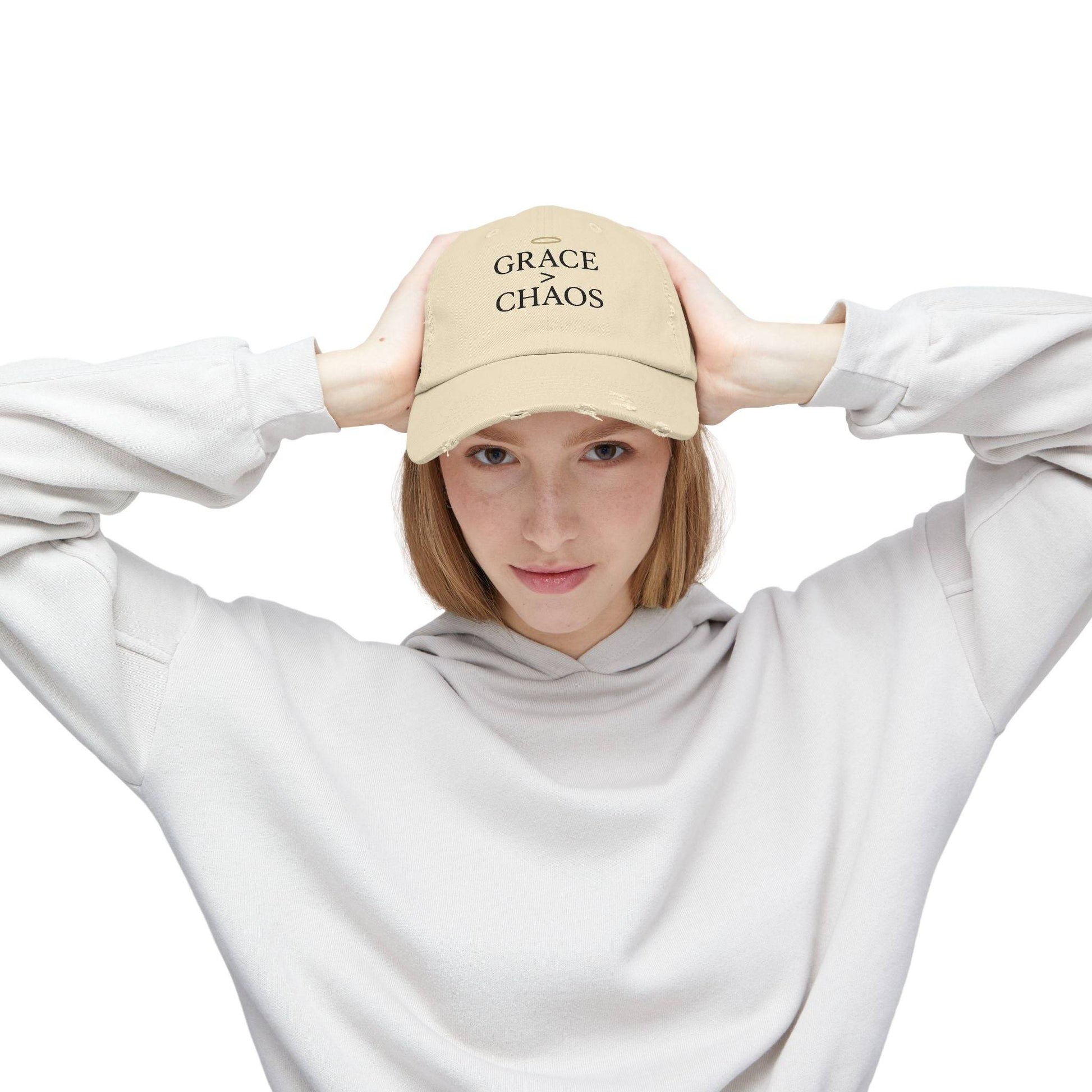 Woman modeling beige Grace > Chaos Embroidered Distressed Cap, a faith-inspired baseball hat for casual and spiritual fashion.