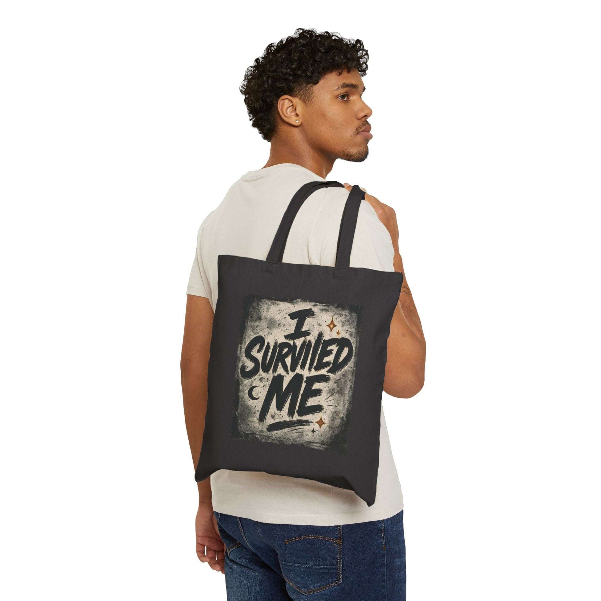 Man carrying black 'I Survived Me' tote bag over shoulder, showcasing a stylish and empowering canvas bag for everyday use.